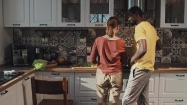 Afrika kökenli Amerikalı bir adamın, kafkas kız arkadaşına sarılıp, evde yemek pişirmesi.