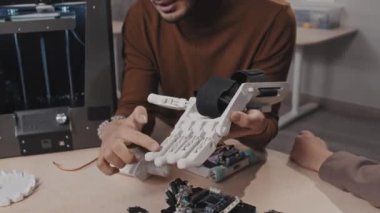 Genç Ortadoğu Robot Bilimi öğretmeninin portresi öğrencilerine hareket mekaniğinden bahseden yapay eli gösteriyor.