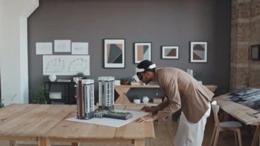 VR gözlüklü profesyonel çift ırklı erkek mimarın gündüz vakti ofisteki apartman planına bakıyor.
