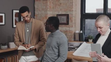 Baş mimarın eğilmesi şehir planlarını gündüz vakti masada duran meslektaşlarına sunuyor.