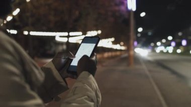 Tanımlanamayan siyahi adam elinde akıllı telefon tutuyor. Taksi uygulaması kullanarak gece geç saatte araba talep ediyor. Seçici odak atışı.