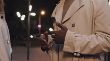 Akşamları dışarıda durup bazı konuları tartışan tanınmamış siyahi adam ve Kafkasyalı kadın iş arkadaşının orta bölümü.