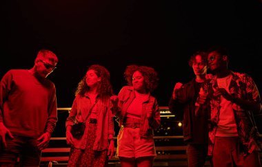 Bir grup mutlu kültürler arası arkadaş çatı partisi sırasında dans ediyor ve geceleri açık kafede toplanıp eğleniyorlar.