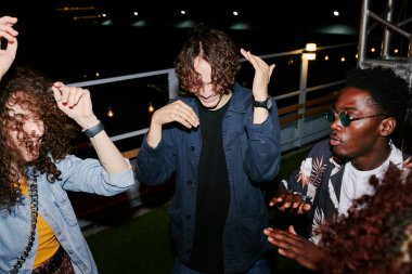 İki kültürlü kültürlü ve şık çift gece vakti çatıda dans ederken açık kafede eğleniyorlar.