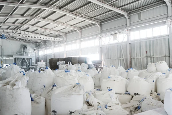 工業生産のための緩い原料を含む巨大な白い袋のヒープを持つ広々とした倉庫や貯蔵室の一部 — ストック写真