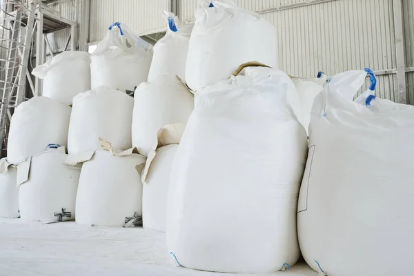 広々とした倉庫や貯蔵室での生産プロセスのために調製された緩い原料を含む巨大な白い袋のヒープ — ストック写真