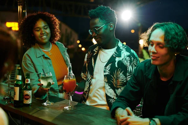 年轻男子和非洲裔美国人夫妇在夜总会 酒吧或户外咖啡馆里享受派对时 他们在柜台边喝酒 — 图库照片