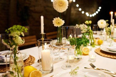 Şarap kadehleri, mumlar, yıldız çiçekleri ve lüks bir restoranda düğün ziyafeti için hazırlanmış diğer süslemelerle birlikte yemek masasının yakın çekimi.