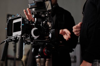 Modern Steadicam, video fotoğrafçısına ve siyah günlük kıyafet asistanına karşı stüdyoda çalışma anlarını tartışıyor.