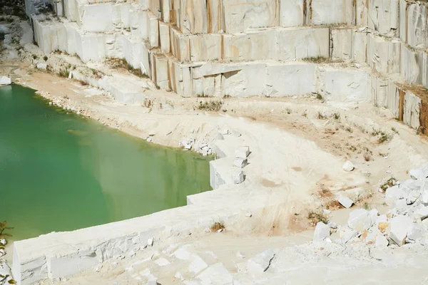 巨大な白いブロックで構成された厚い壁によって小さな池と大理石の採石場で近代的な生産工場の周囲の領土の一部 — ストック写真