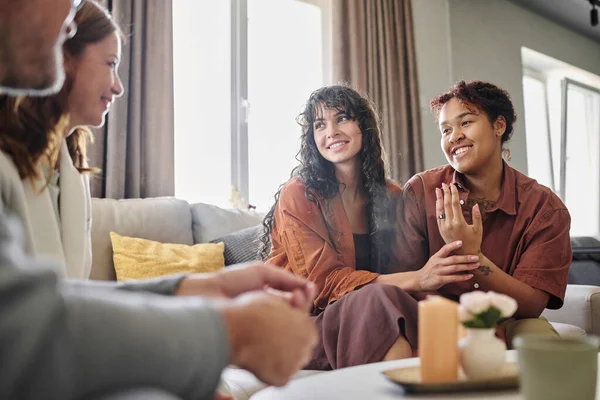 stock image Happy young multi-ethnic woman showing engagement ring on her finger while talking to parents of her girlfriend in living room