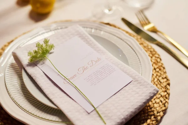 折り畳まれた綿ナプキンと提供テーブル上のテキストとカード上の小さな緑の装飾植物と白い磁器プレートのクローズアップ — ストック写真