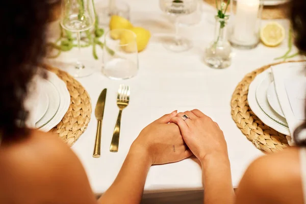 在女同性恋婚宴上 两个年轻的跨文化新娘手拉手端餐桌 坐在一起的特写镜头 — 图库照片