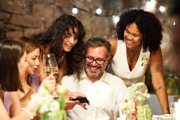 快乐的年轻黑发新娘弯腰面对快乐的成熟男人 用智能手机向她的父母和朋友展示新照片 — 图库照片