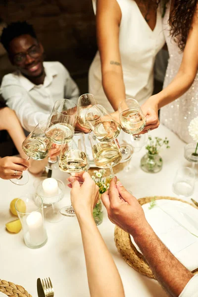 在餐厅里 宾客们手拉手地围坐在摆满香槟酒的节日餐桌前 为新婚夫妇们敬酒 — 图库照片