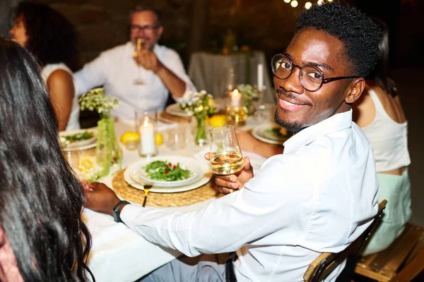 Счастливый Молодой Афроамериканец Шампанской Флейтой Сидящий Сервированным Столом Веселящийся Друзьями — стоковое фото