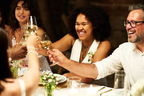 快乐的非洲裔美国新娘 穿着婚纱和朋友们一起敬酒 一边享用节日餐桌 一边享受派对 — 图库照片