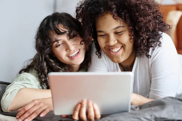 两个快乐的女友 带着平板电脑在视频聊天中交流 或者早上在床上休息时选择在线商品 — 图库照片