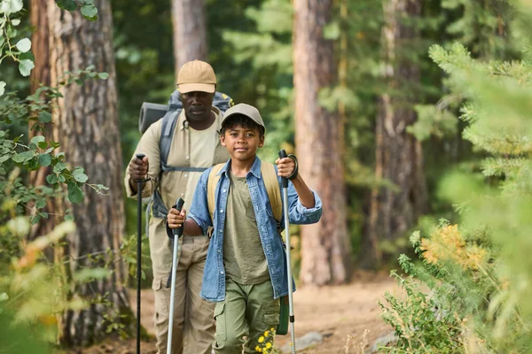 Słodki Chłopczyk Kijami Trekkingowymi Poruszający Się Wąską Ścieżką Patrzący Kamerę — Zdjęcie stockowe