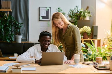 Dizüstü bilgisayara bakıp verileri tartışırken yeni iş projesinin sunumunu hazırlayan iki başarılı genç iş arkadaşı