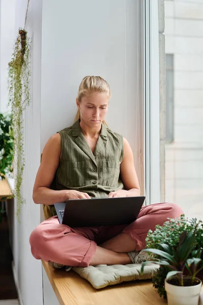 Jonge Serieuze Blonde Vrouw Casualwear Met Laptop Haar Gekruiste Benen — Stockfoto