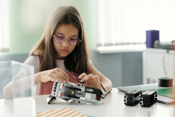 Cute Serious Schoolgirl Creating Robot Model Machine Lesson While Sitting — Stock Photo, Image