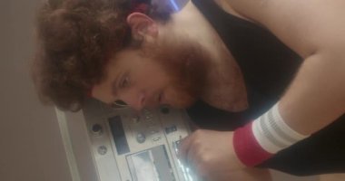 Retro aerobik kıyafetli beyaz bir adamın gündüz vakti fitness stüdyosunda elinde teyp ile dikey bel portresi.