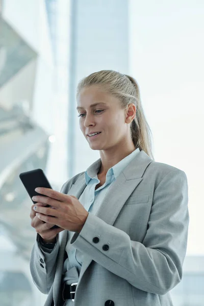 同僚とビデオチャットで通信しながら 自分の前でスマートフォンを保持若いブロンドのビジネス女性の肖像画 — ストック写真