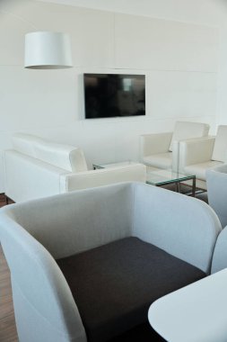 Geniş açık uzay ofisindeki diğer mobilyaların arka planında kameranın önünde duran siyah ve gri kadife koltuk.