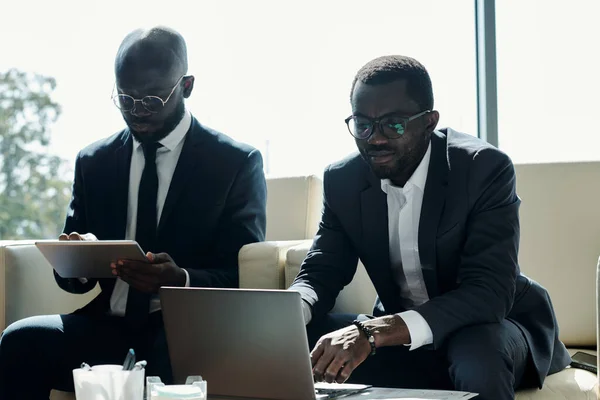 Młodzi Poważni Afroamerykanie Męscy Współpracownicy Korzystający Tabletu Laptopa Podczas Siedzenia — Zdjęcie stockowe