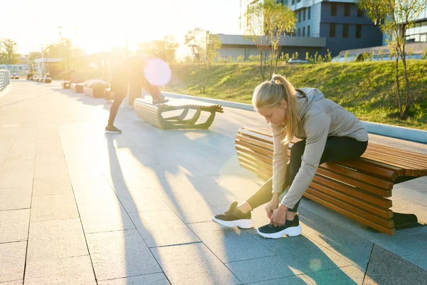 Young Blond Sportswoman Activewear Sitting Bench Urban Environment Bending Sneaker — Stock Photo, Image