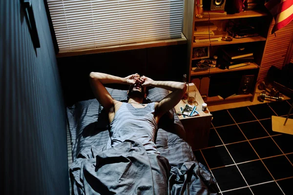 有创伤后综合症的青年不眠者躺在床上 双手紧握 患有失眠或头痛 — 图库照片
