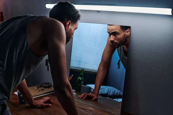정신적 질환을 테이블 구부리고 불면증으로 고생하는 거울에 자신의 모습을 바라봅니다 — 스톡 사진