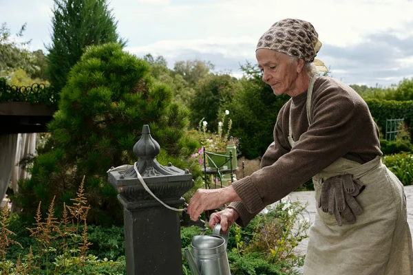 Senior Woman Apron Workwear Taking Clean Water Watering Pot While — Stock Photo, Image