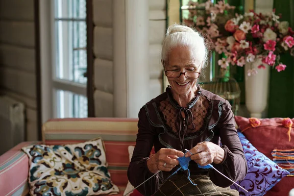 幸せな祖母でスマートキャミソールに座っていると編む暖かいウール冬服のために彼女の家族 — ストック写真
