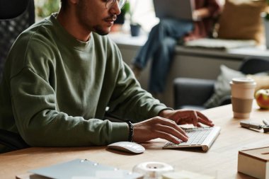 İş yerinde bayan meslektaşlarına karşı otururken eşofmanlı genç işadamlarının bilgisayar klavyesinde daktilo yazışmaları yakın plan.