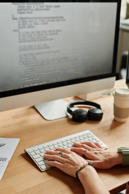 Genç iş kadını ya da programcı monitör ve veri çözme masasının önünde otururken bilgisayarın klavyesine basıyor