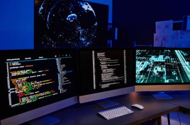 Birkaç modern bilişim mühendisi veya programcısının mekanlarında duran ekranlarda şifreli verileri olan üç bilgisayar monitörü.