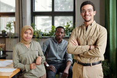 Müslüman kadın ve Afrikalı Amerikalı adama karşı kameranın önünde duran çok kültürlü iş adamlarının mutlu genç lideri.