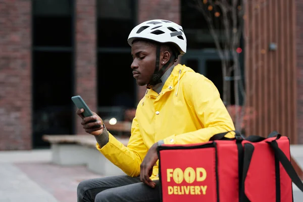 Sarı Ceketli Kasklı Kentsel Ortamda Oturan Akıllı Telefon Kullanan Dinlendirici — Stok fotoğraf