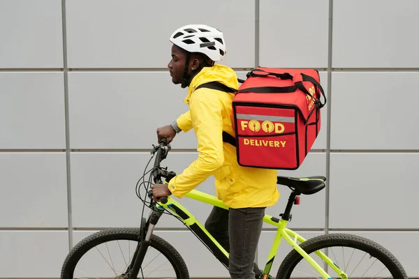 Sarı Ceketli Afro Amerikan Yemek Servisi Çalışanı Bisikletli Gri Bina — Stok fotoğraf