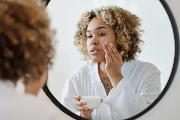 Ung Attraktiv Kvinna Som Applicerar Återfuktande Kräm Ansiktet Framför Spegeln — Stockfoto