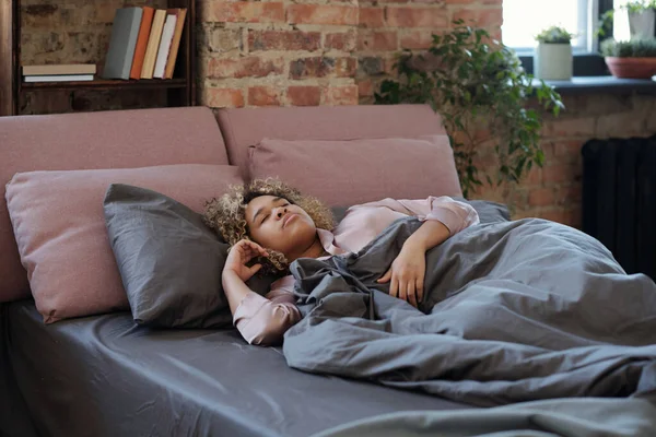 ベッドで午前中にグレー毛布の下で彼女の頭とともにピンクの枕 — ストック写真
