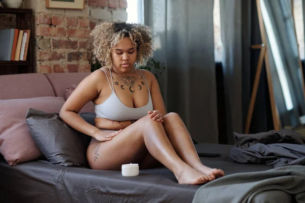 Çıplak Ayaklı Afro Amerikan Kız Yatakta Otururken Bacak Derisine Bakıyor — Stok fotoğraf