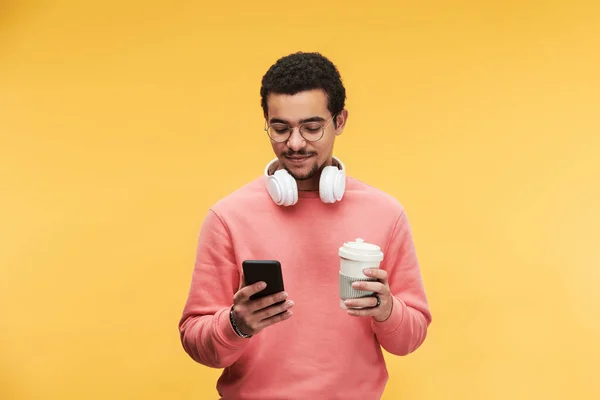 Beyaz Kulaklıklı Akıllı Telefon Kullanan Sarı Arka Planda Kahve Içen — Stok fotoğraf