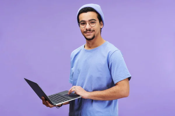 年轻的成功学生或设计师 身穿蓝色T恤 头戴便帽 手持笔记本电脑 背对着薰衣草背景看相机 — 图库照片