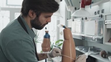 Yüzünde sakalı olan beyaz bir adamın insan bacağı protezi için alçıya alınmış sıvı plastikle soket şeklindeki fotoğrafını eğ.