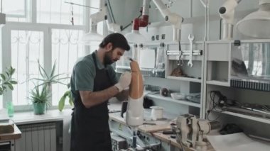 Modern bir zanaatkar protez bacak soketi yapmak için insan kalçası alçısına sıvı plastik yayıyor.