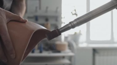 Silikonun veya plastik soketin kenarlarını pürüzsüz hale getirmek için öğütücü kullanarak protez uzuv üzerinde çalışan tanınmayan zanaatkârın yakın çekimi