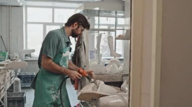 Önlük ve koruyucu gözlük takan profesyonel bir zanaatkar protez kol soketi için alçıda delik açıyor.